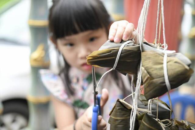 6月18日，一个女孩在马来西亚马六甲修剪粽子叶。当地举行了游龙舟和裹粽子等活动。新华社记者程一恒摄