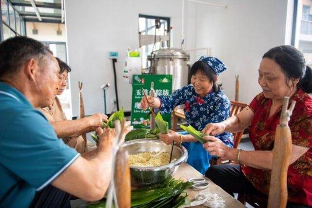  6月22日，在湖南省汨罗市屈子祠镇新义村，村民们在包粽子。新华社记者陈思汗摄