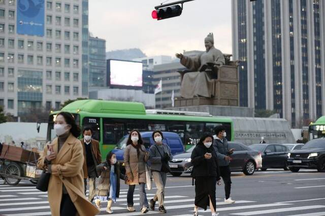 2021年11月29日，行人佩戴口罩在韩国首尔光化门广场过马路。新华社记者王益亮摄