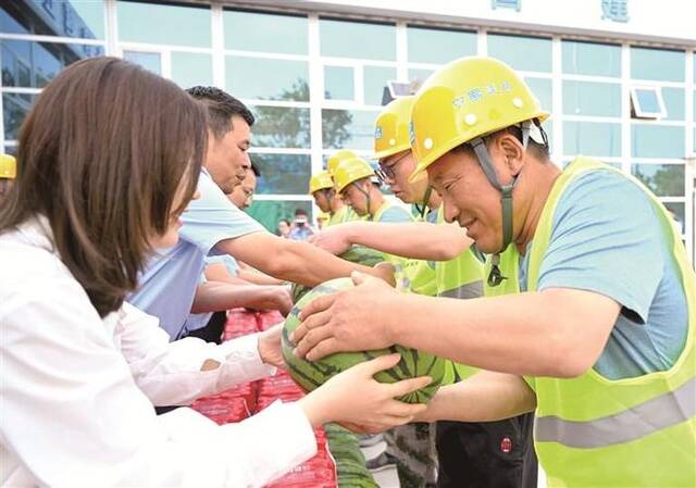 图为近日，在天津市滨海新区耀华中学滨海学校项目工地，中建二局四公司工作人员为一线工人送去西瓜。新华社记者赵子硕摄