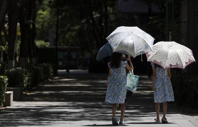 7月6日，北京朝阳，由于气温高、日照强，小朋友打着太阳伞遮阳。新京报记者陶冉摄