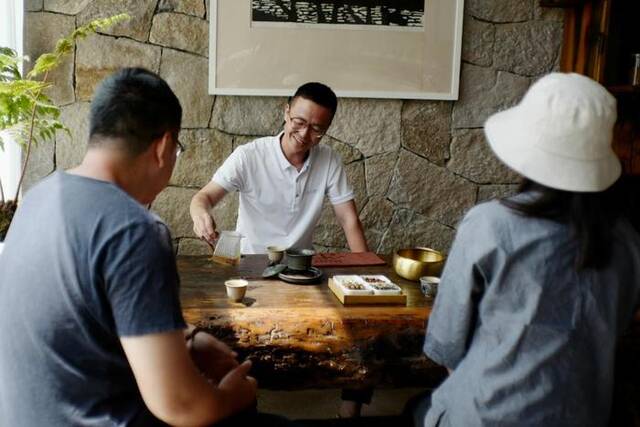 浙江温岭石塘一家民宿内，民宿管家林波在茶桌前与住客饮茶聊天。新华社记者徐中哲摄