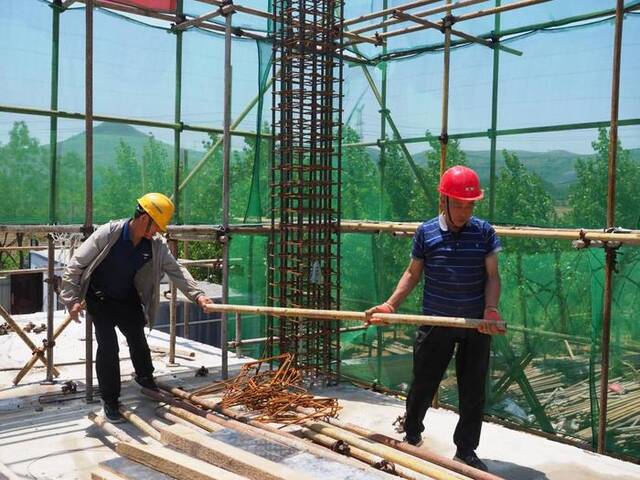 在山东省枣庄市峄城区龙泉庄水库水厂施工现场，工人正在搬运钢管。新华社记者高天摄