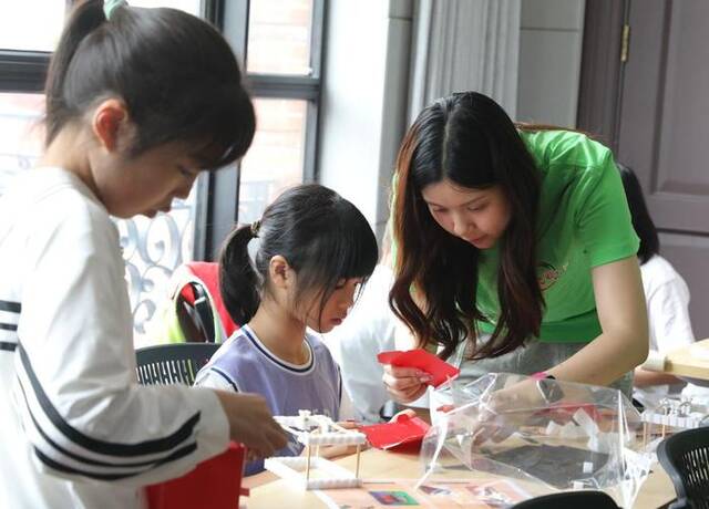 7月3日，在上海静安区，志愿者带领爱心暑托班的孩子们通过手工体验非遗文化。新华社记者刘颖摄