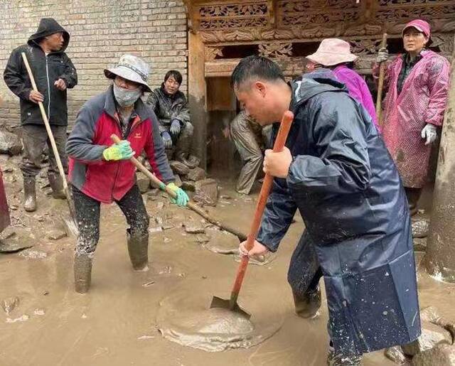 县纪委监委干部与当地干部群众一起清理淤泥。（马婧摄）