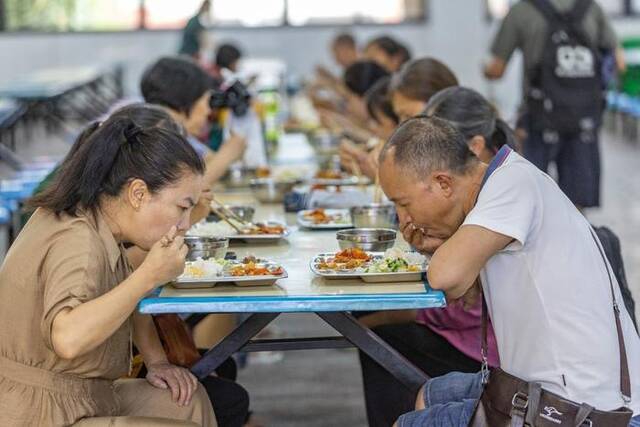 7月14日，在重庆市万州三中江南校区临时安置点内，转移安置人员在就餐。新华社记者黄伟摄