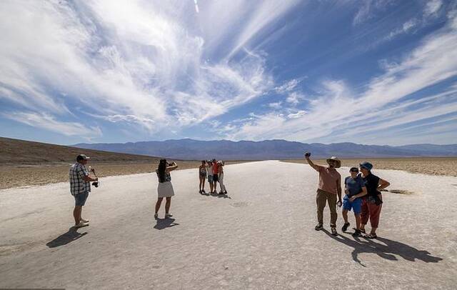 当地时间2023年7月16日，美国加州，死亡谷国家公园，随着气温上升到120华氏度以上，人们走在坏水盆地的盐滩上。