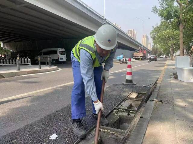 7月20日，北京排水集团工作人员对雨水口清掏，保障安全度汛。（北京排水集团供图）