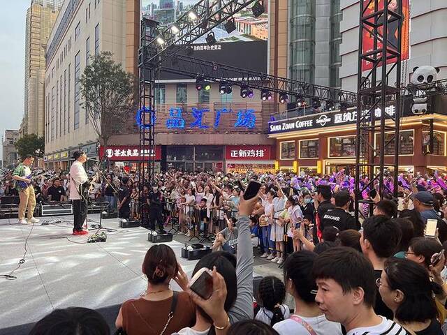 7月22日晚，湾里庙步行街舞台，码头薯条乐队在表演，台下的观众打开手机闪光灯一起大合唱。