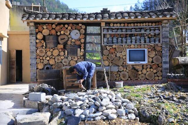 图为村民在院子里用废旧物品搭建的文化墙。（张文灿摄）