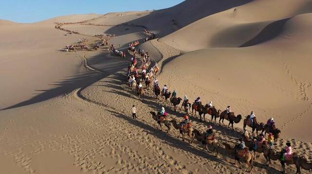 在大漠中行走的驼队。图源：鸣沙山月牙泉景区公众号