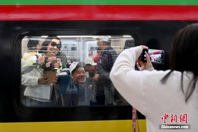 中老铁路国际旅客列车正式开行，旅客手捧鲜花拍照留念。中新社记者李嘉娴摄