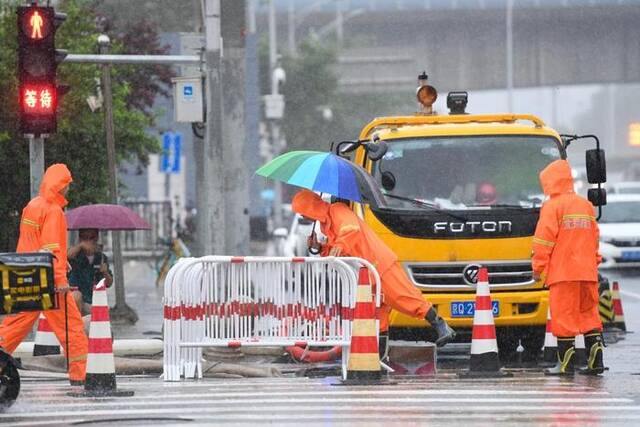 7月30日，在北京市朝阳区十里河桥附近，北京排水集团的工作人员在检查雨水井。新华社记者鞠焕宗摄