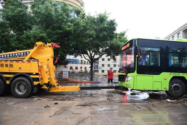 7月31日，抢险人员在北京市门头沟区新桥大街救援抛锚的公交车。新华社记者鞠焕宗摄