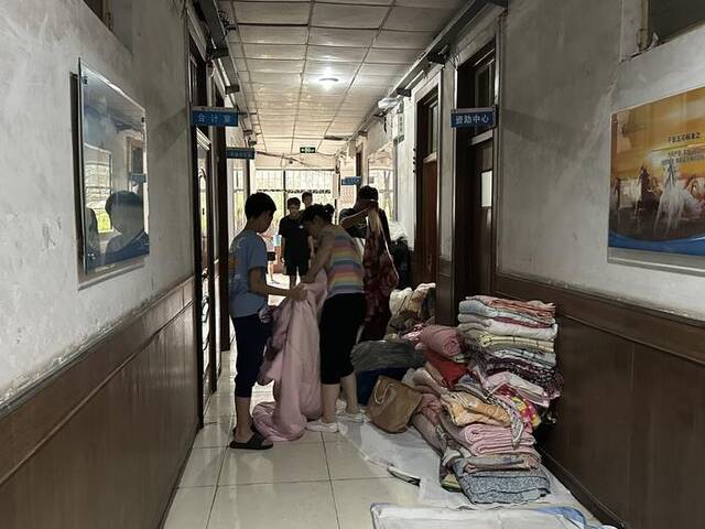 在涿州职教中心的临时指挥部内人来人往，走廊里堆满了方便面、饮用水、被褥等应急物资。新京报记者姜慧梓摄