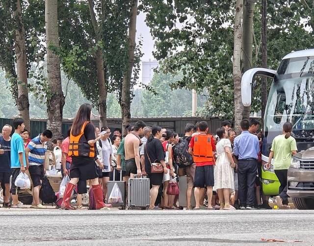 8月3日，涿州北二环路，乘坐皮划艇转运到安全位置后，居民排队登上前往安置点的大巴。新京报记者陶冉摄