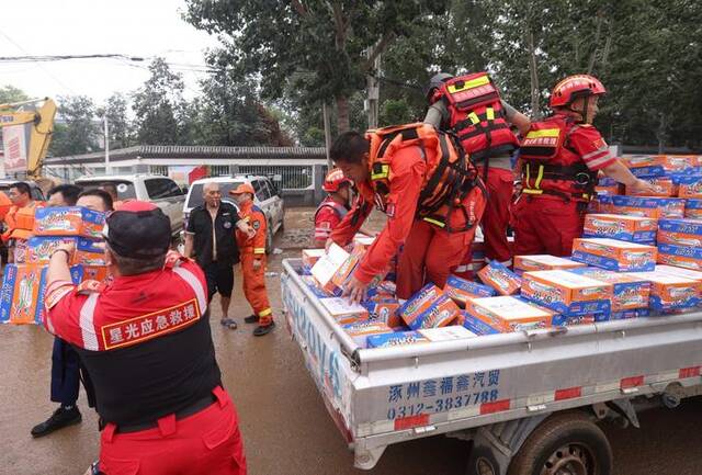 8月3日，涿州北二环路，救援人员为民众发放物资。新京报记者陶冉摄