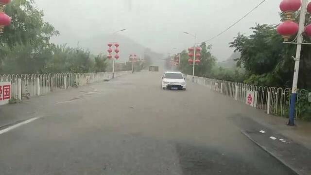 7月31日的丁家滩村牌坊通往村子的道路，永定河水位已经快速上涨。受访者供图