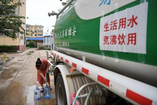 8月4日，河北省涿州市新星小区居民从供水车里接水。新华社图