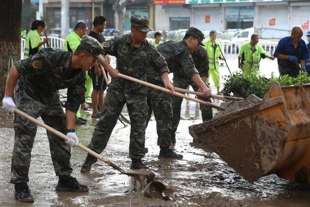 武警河北总队保定支队官兵在涿州市城西107国道沿线清理淤泥（8月5日摄）。新华社发（王红强摄）