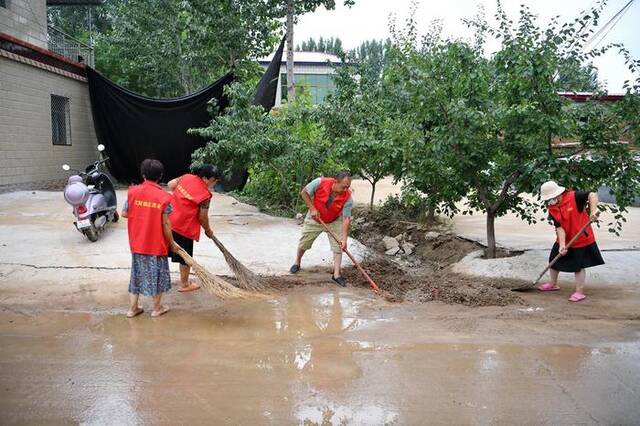 8月6日，在河北涿州刁窝镇白塔村，志愿者在街道上进行清淤作业。