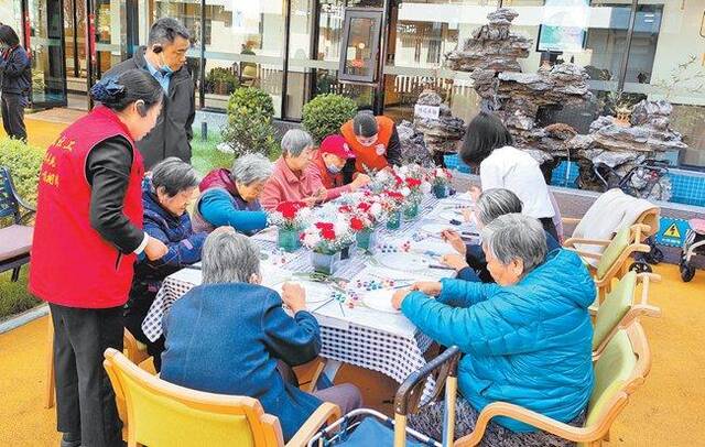 郑州市中原区建设路街道养老服务中心，老人在社工指导下学习插花技艺。