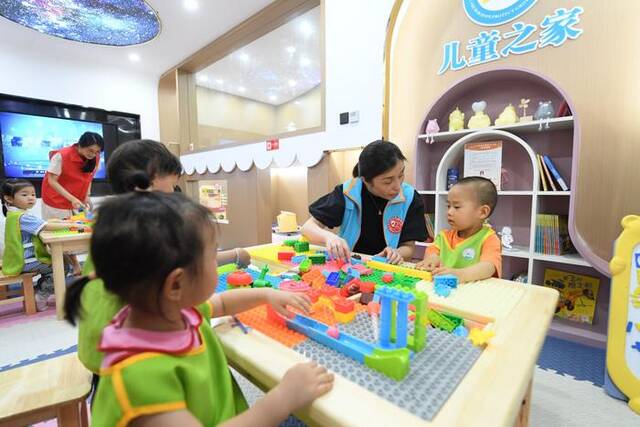 2023年5月29日，在浙江省湖州市爱山街道利民社区，一个公益组织的老师带着儿童玩积木。新华社记者翁忻旸摄
