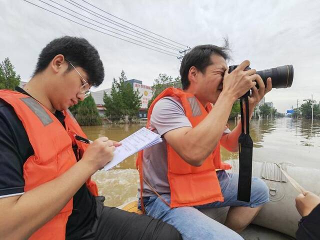 新华社记者杜一方（左一）在记录街道积水情况。新华社记者高博摄