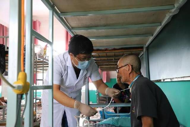 在廊坊市文安县苏桥镇临时集中安置点，医生正在为一名转移安置群众进行术后护理。（受访者供图）
