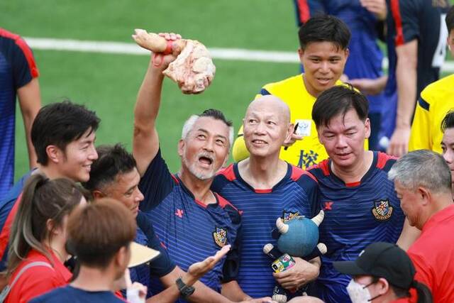 8月13日，香港明星队球员举起作为比赛奖品的猪蹄。新华社记者刘续摄