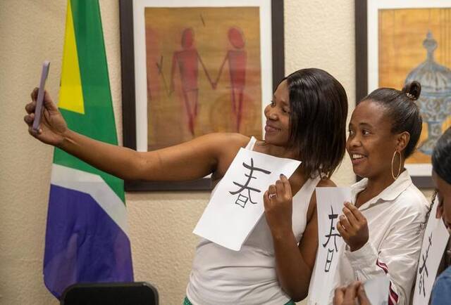 4月19日，南非约翰内斯堡大学孔子学院学生拿着自己的书法作品自拍。