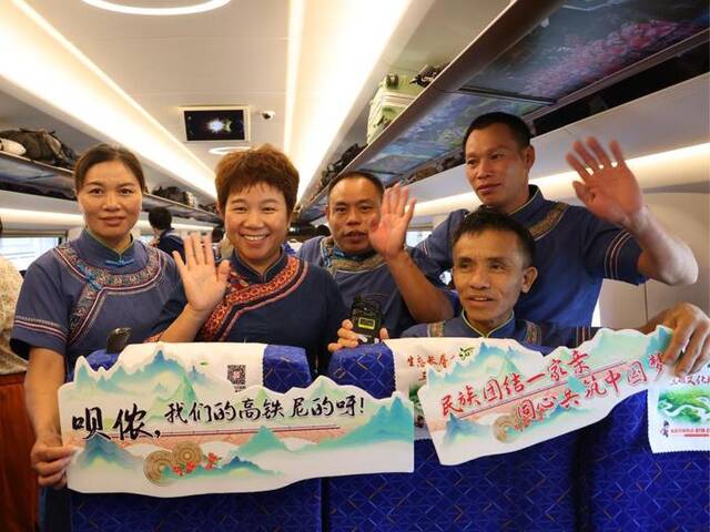 谭美春（前左二）同毛南族群众在车厢内欢庆贵南高铁全线开通运营。新华社发（林鹤摄）
