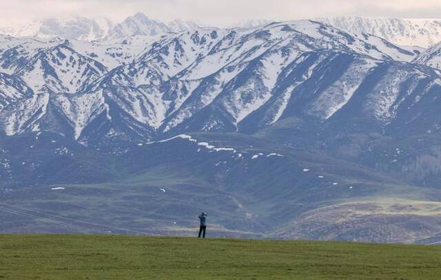 游客在新疆塔城地区裕民县巴尔鲁克山区拍摄风景（2023年5月2日摄）。新华社发（张度摄）