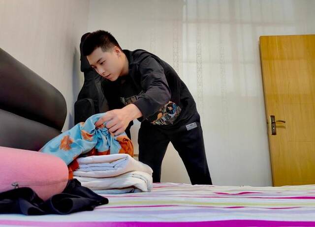 杨志洋正在收拾妈妈的卧室。新华社记者孙正好摄