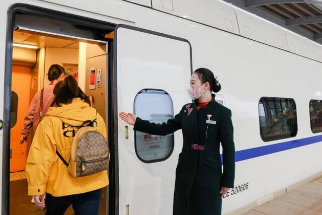 2023年3月17日，列车员李泓祁在乌鲁木齐站引导乘客乘车。新华社记者郝昭摄
