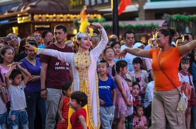 在乌鲁木齐大巴扎景区，游客和演员一起跳舞（2019年7月24日摄）。新华社记者王菲摄
