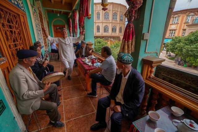 在新疆喀什古城景区内的百年老茶馆阳台上，当地居民在跳舞、聊天（2020年5月17日摄）。新华社记者赵戈摄