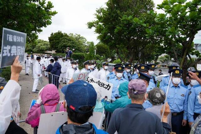 2022年5月15日，在日本冲绳，警察在冲绳回归日本本土50周年纪念仪式现场外阻拦抗议者。新华社记者张笑宇摄