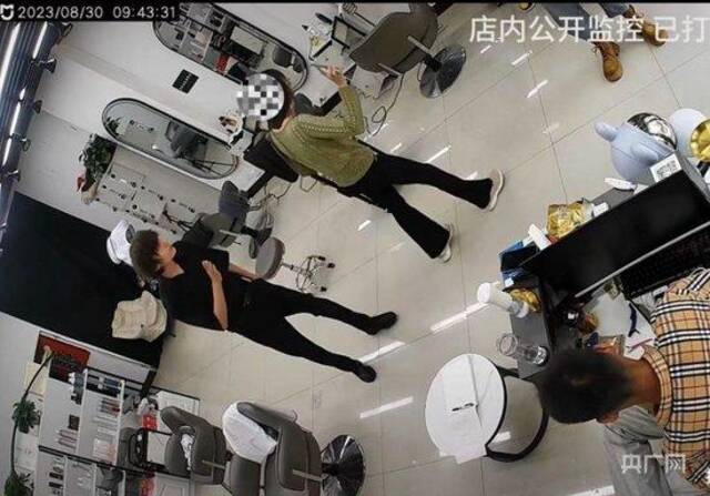 女子出示证件威胁店主（央广网发理发店视频监控截图）