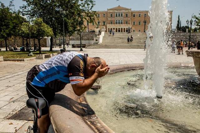 7月12日，在希腊首都雅典，男子在喷泉处洗脸纳凉。新华社发（帕纳约蒂斯·莫斯卡德里欧摄）