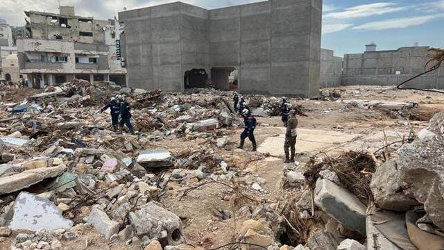 9月17日，国际救援人员在利比亚德尔纳的建筑废墟上工作。新华社发（哈姆扎·图尔基亚摄）