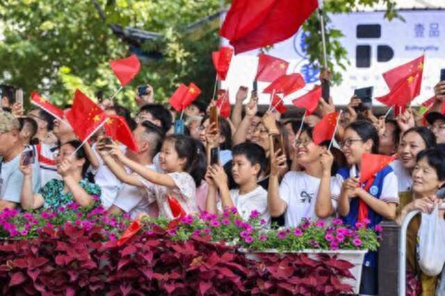 2023年9月17日，杭州亚运会火炬传递金华站现场，市民为火炬手加油喝彩。记者朱海伟吕之遥潘海松金思成摄