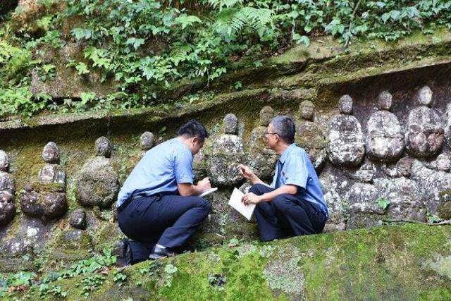 检察官查看庞坡洞摩崖造像被盗佛首情况。