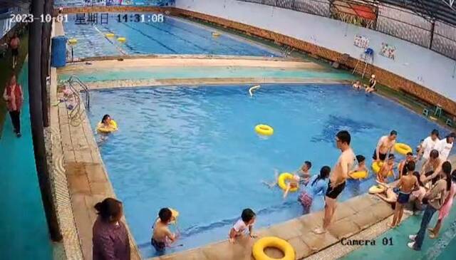 ▲众人在泳池边对男童展开抢救监控视频截图