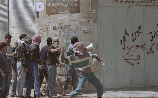 1988年，在约旦河西岸，人们站在墙边扔瓶子。