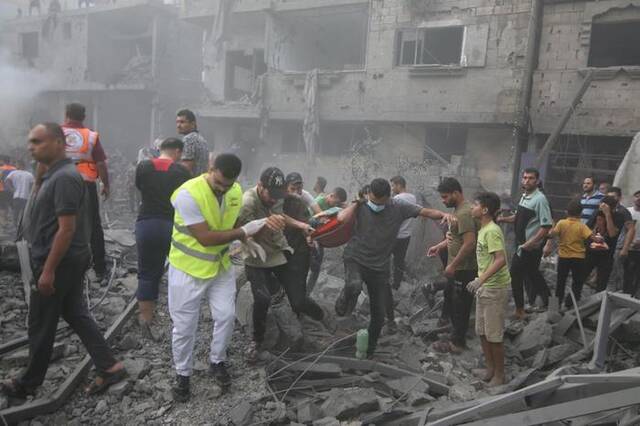 10月12日，在加沙地带南部城市拉法，人们在遭以色列空袭的受损建筑中救援伤者。新华社发（哈立德·奥马尔摄）