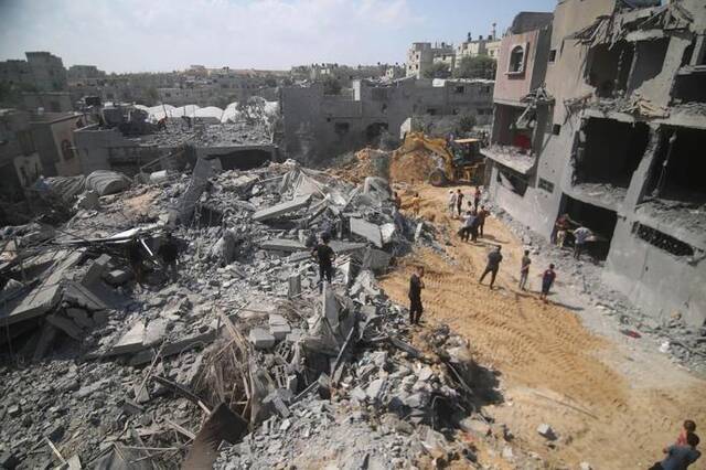10月12日，在加沙地带南部城市拉法，人们查看遭以色列空袭的受损建筑。新华社发（哈立德·奥马尔摄）