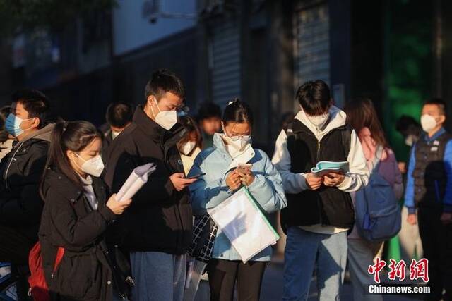 1月8日，江西南昌市第二十八中学考点外，几名考生在复习。当日，中央机关及其直属机构2023年度考试录用公务员公共科目笔试举行。中新社记者刘力鑫摄