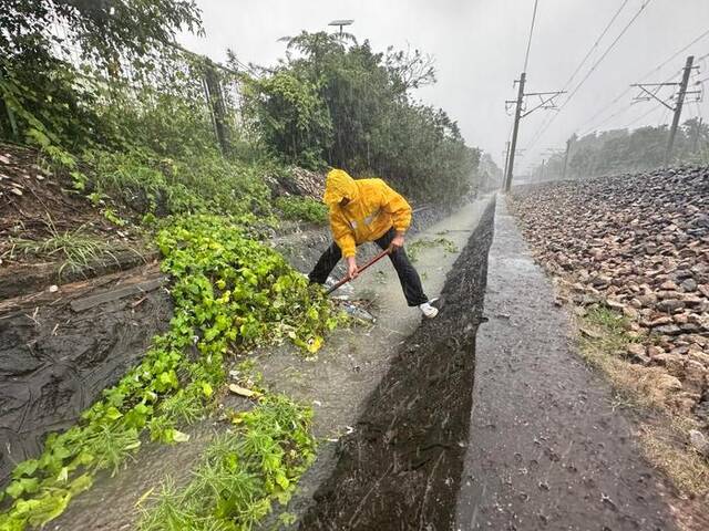 10月19日，在黎湛铁路塘口至遂溪区间，国铁南宁局玉林工务段职工在冒雨清理铁路两侧水沟。（刘毅摄）