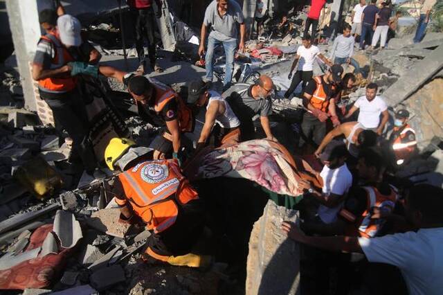 10月20日，人们在加沙地带南部城市拉法遭以色列袭击损毁的建筑废墟上实施救援。新华社发（哈立德·奥马尔摄）